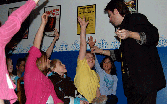 Kids raising their hands at a show to volunteer